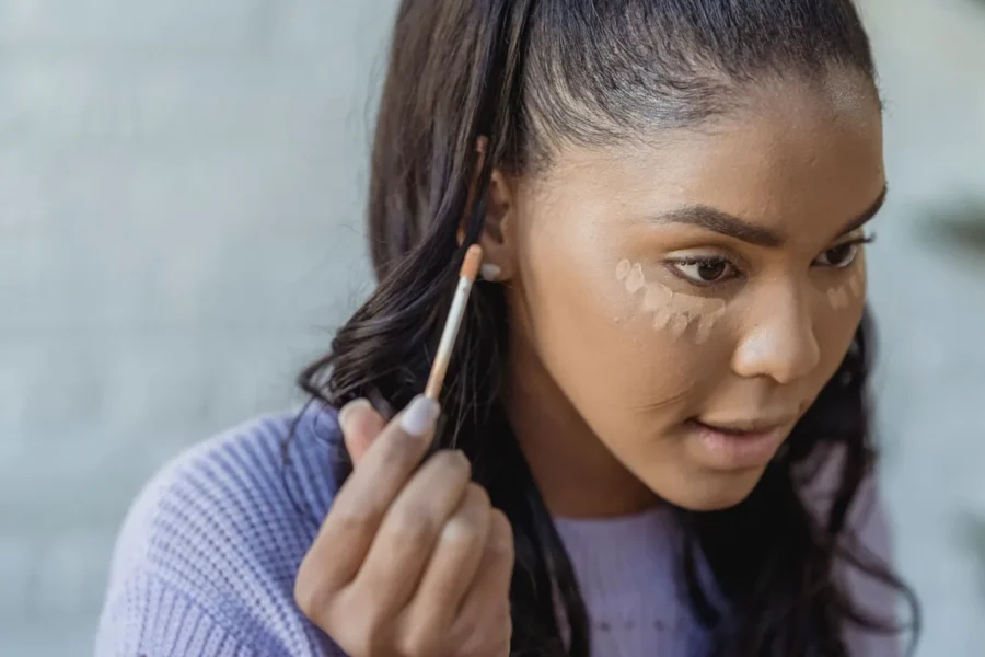 Woman applying concealer bright makeup