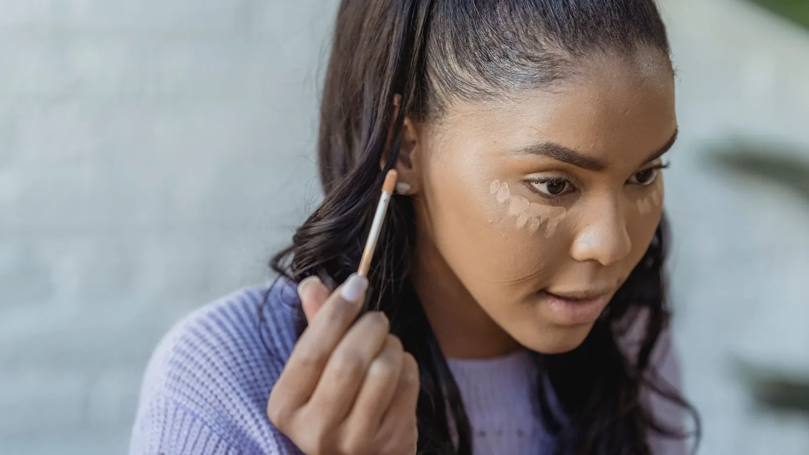Woman applying concealer bright makeup